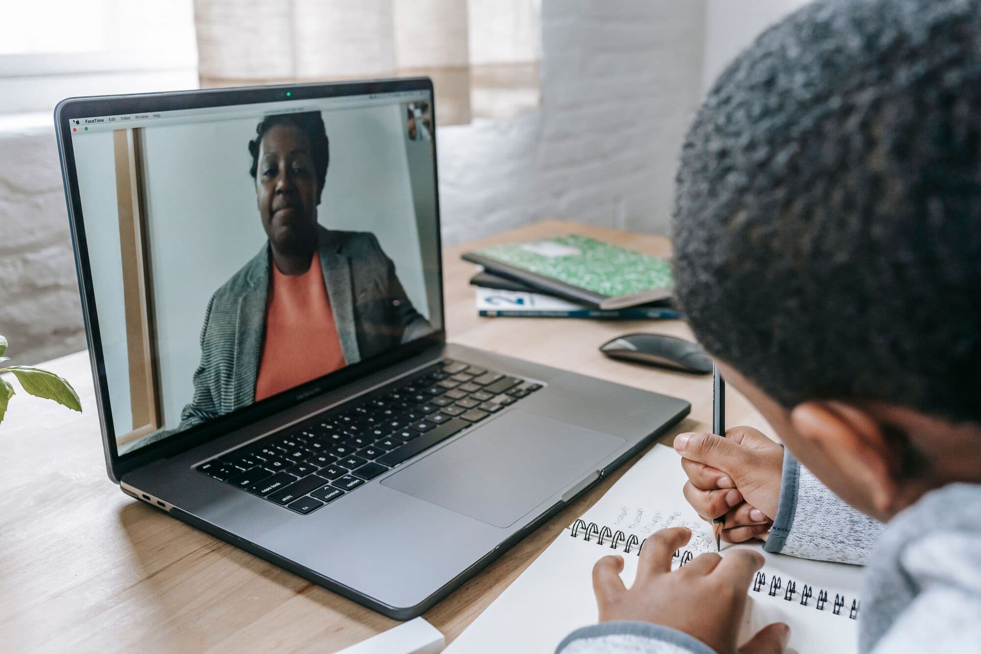 A learner writes during a live video lesson with his tutor